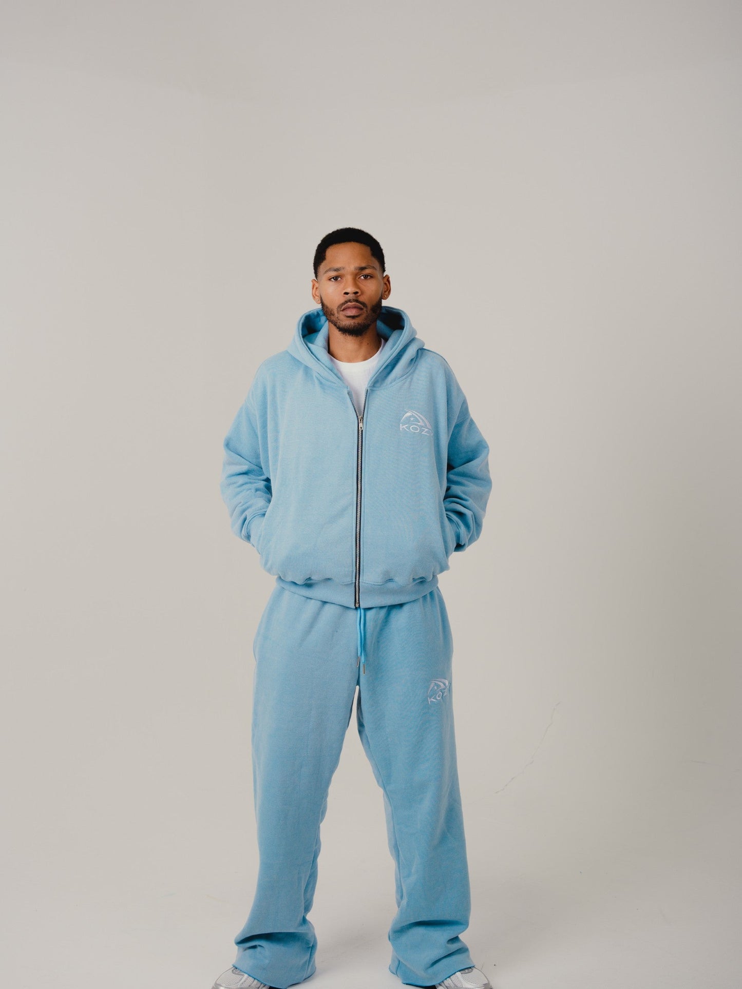 Person wearing a light blue tracksuit on a plain background