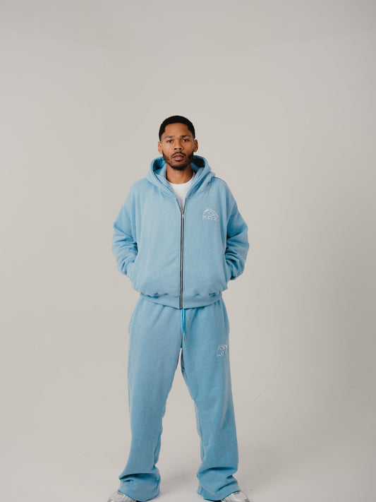 Person wearing a light blue tracksuit on a plain background
